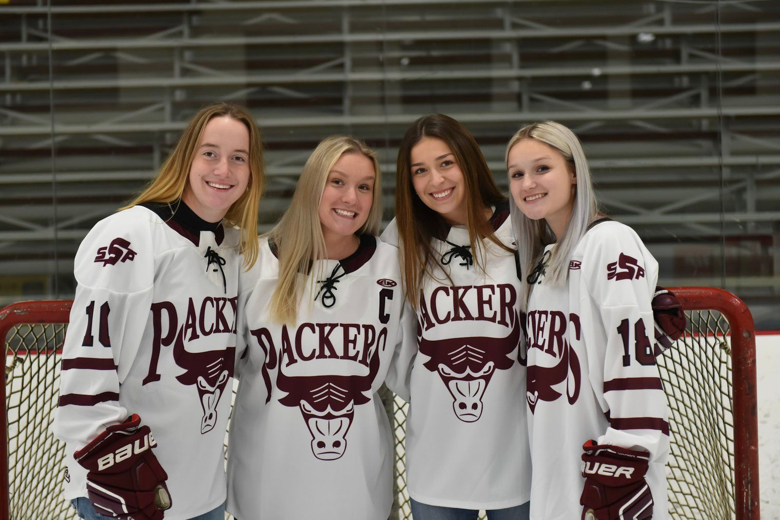 Four Packers players posing in front of the net